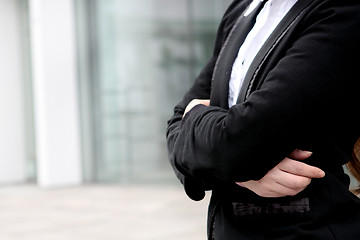 Image showing Young businesswoman standing with folded hands, modern building 