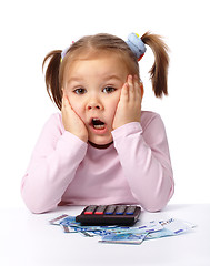 Image showing Little girl plays with money, making shocked face