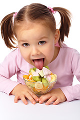 Image showing Little girl licks fruit salad