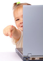 Image showing Cute little girl is looking out from her laptop