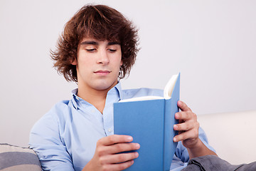 Image showing man seated reading a book on couch