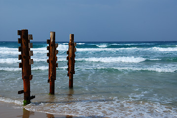 Image showing Old rusty pier piles on sea shore