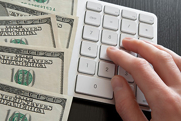 Image showing Counting money on computer calculator