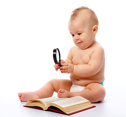 Image showing Little child play with book and magnifier