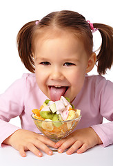 Image showing Little girl licks fruit salad