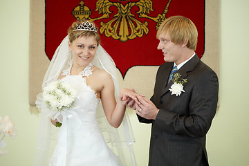 Image showing Groom solemnly puts ring on bride