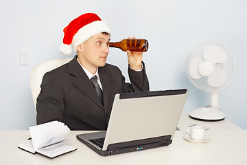 Image showing Funny man in New Year's hat looks through a bottle