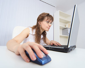 Image showing Amusing woman attentively studies Internet by means of laptop