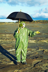 Image showing Man in gas mask with umbrella waiting for acid rain