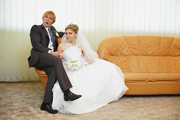 Image showing Amusing groom and bride sitting on armchair