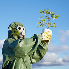 Image showing Man in chemical suit and gas mask with plant in hands