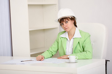 Image showing Girl engineer in white helmet on workplace at office