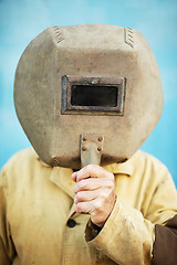 Image showing Old welder's helmet in hands of welder