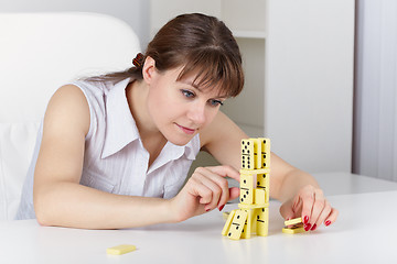 Image showing Young woman plays with dominoes