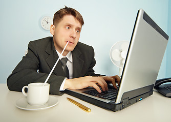 Image showing Businessman drinks coffee through a straw and work in Internet