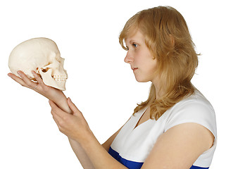 Image showing Woman examines a human skull on white