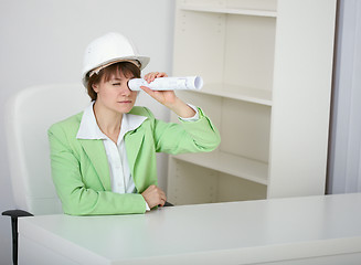 Image showing Amusing woman engineer in helmet looks through drawing