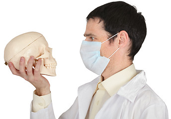 Image showing Student medical school in mask looks at skull