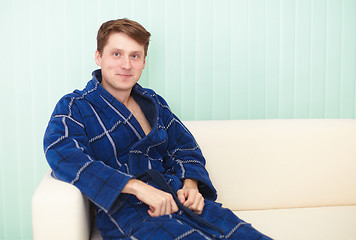 Image showing Guy sitting on a couch in blue gown