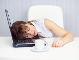 Image showing Young woman comically asleep on keyboard at table