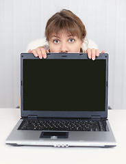 Image showing Young girl hiding behind a laptop screen