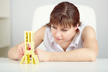 Image showing Girl is focused to build a tower with domino on table