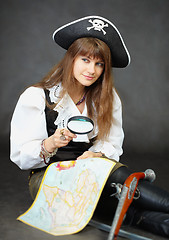 Image showing Girl - pirate sitting with a map and magnifying glass