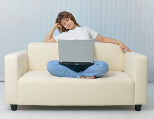 Image showing Beauty is sitting on sofa with laptop