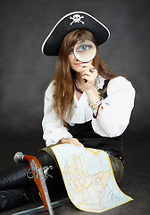 Image showing Woman pirate, and map with a magnifying glass on black backgroun