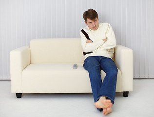 Image showing A gloomy man sitting on couch in front of TV