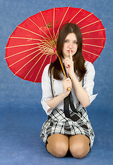 Image showing Girl with red oriental umbrella on blue