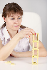 Image showing Woman builds precarious tower of dominoes