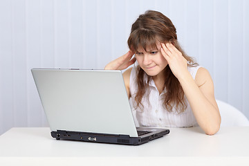 Image showing Young woman concentrated thinks sitting at table with laptop