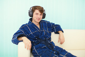 Image showing Man in big ear-phones sits on sofa
