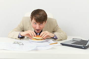 Image showing Hungry businessman eats tasty sandwich