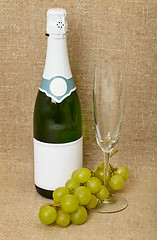 Image showing Bottle of sparkling wine, glass and grapes on canvas - still lif