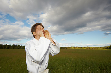 Image showing A man shouting into field