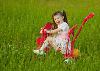 Image showing Cheerful little girl goes on a bicycle