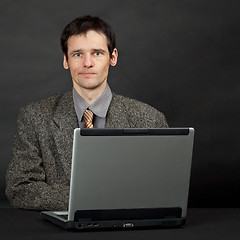 Image showing Young man sitting at table with computer
