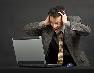 Image showing Ðoung man shouts with despair looking at computer screen