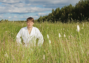 Image showing Young man in white kimono sits in grass