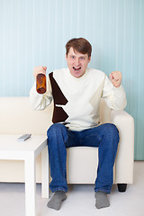 Image showing Football fan sitting on sofa with TV and beer