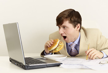 Image showing Young businessman is going to eat sandwich