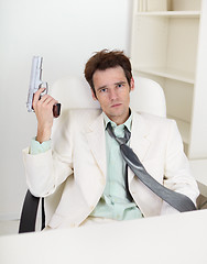 Image showing Young, strong-minded businessman with gun in hand