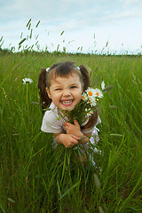 Image showing Cheerful child embraces wild flowers