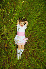 Image showing Little girl lies in green grass