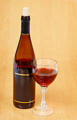 Image showing Bottle of red wine and glass on wooden table