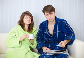 Image showing Couple in dressing gowns sitting on couch and watching TV in dis