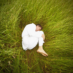 Image showing Man lying on grass in fetal position