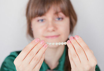 Image showing Young girl admires a beads from pearls